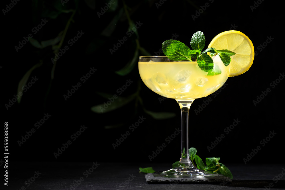 White lady alcoholic cocktail with dry gin, liquor, lemon juice and ice in glass. Bartender pours cocktail from shaker into glass. Black background