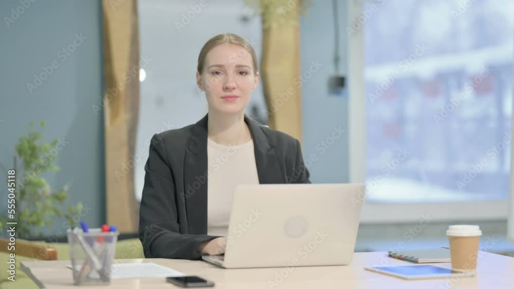 Businesswoman Looking at Camera while using Laptop Businesswoman Looking at Camera while using Laptop