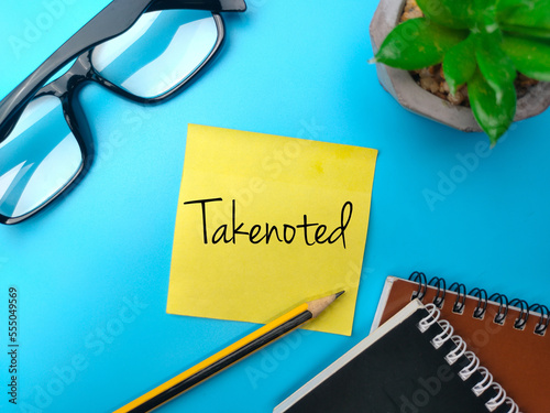 Sticky notes and pencil with the word Takenoted on blue background.