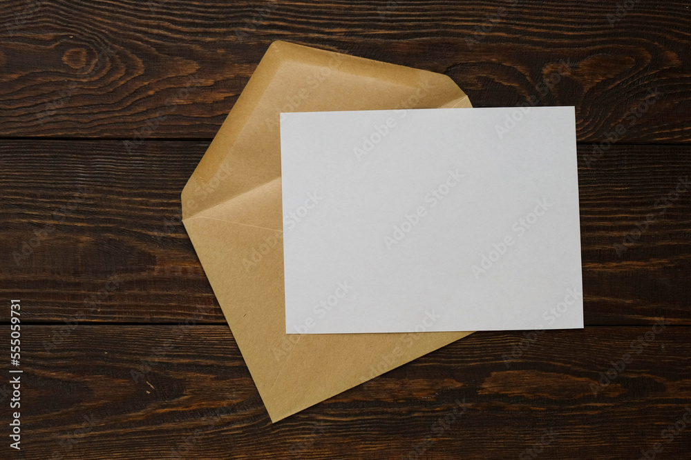 Craft envelope for letters with a blank sheet. Flat lay with a note on a wooden background Craft envelope for letters with a blank sheet. Flat lay with a note on a wooden background