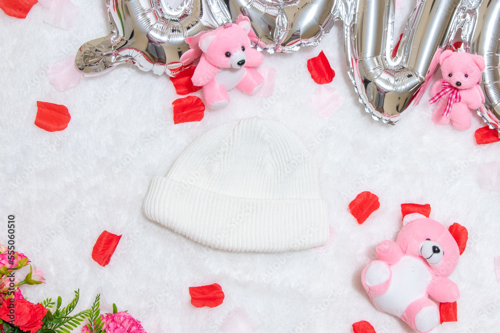 White blank beanie above a fluffy white carpet surrounded by valentine themed decorations White blank beanie above a fluffy white carpet surrounded by valentine themed decorations