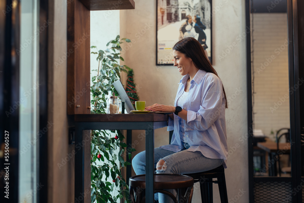 Young beautiful girl sitting in a coffee shop and working on computer Young beautiful girl sitting in a coffee shop and working on computer