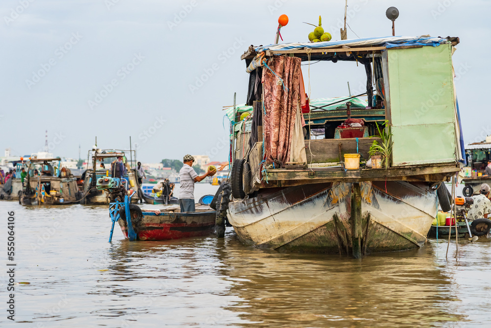Merchants trading goods between rustic wooden boats on a river at Chau Doc in Vietnam