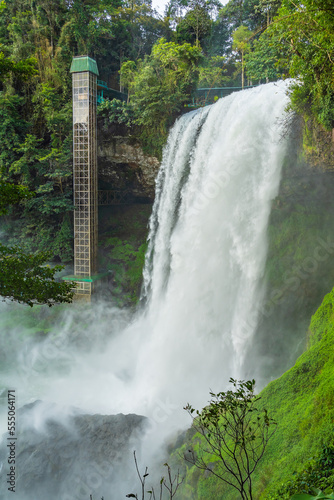 Close up of a large waterfall with a vertical elevator shaft alongside at Dambri Falls in Vietnam photo