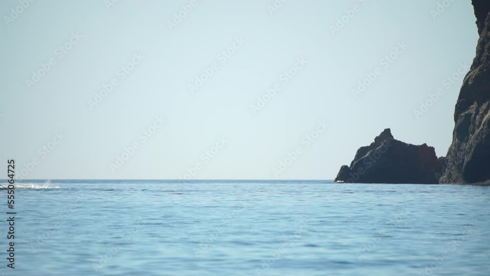 A motorized surfboard with a rider moving on a calm sea. The silhouette of a man on a water scooter glides through the water. Sports and sea activities on a beach holiday. Slow motion. A motorized surfboard with a rider moving on a calm sea. The silhouette of a man on a water scooter glides through the water. Sports and sea activities on a beach holiday. Slow motion.