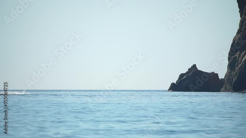 A motorized surfboard with a rider moving on a calm sea. The silhouette of a man on a water scooter glides through the water. Sports and sea activities on a beach holiday. Slow motion. photo