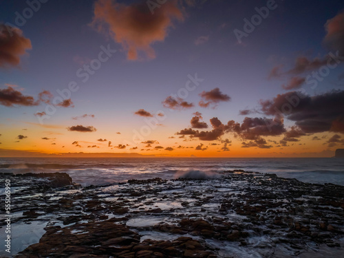 Surfs up sunrise at the seaside with scattered clouds