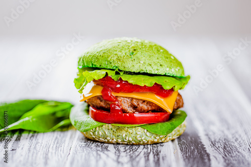 Side view of green burger with artificial meat, fresh greenery on wooden table. Vegetarian food  photo