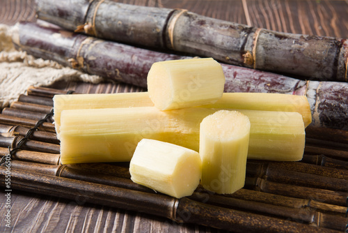 fresh sugarcane with cut pieces on wooden table