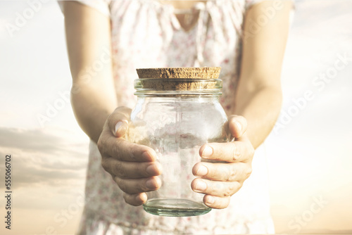 woman showing an empty glass jar that she holds in her hands, concept of economic crisis, savings, poverty