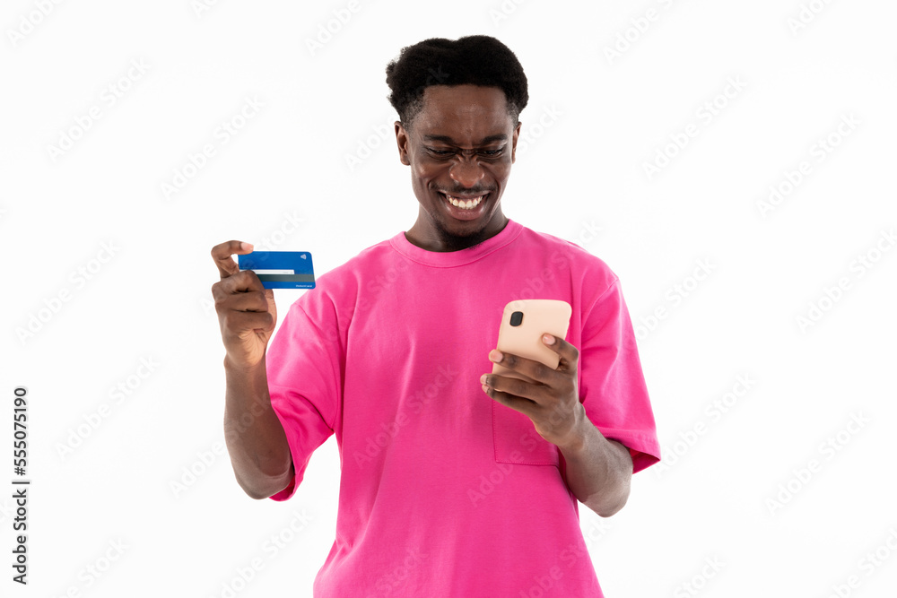 Confused african man looking at phone screen holding credit card and cellphone in hands writing card number making false having problem with payment. Shooting process of bank advertisiment. Confused african man looking at phone screen holding credit card and cellphone in hands writing card number making false having problem with payment. Shooting process of bank advertisiment.