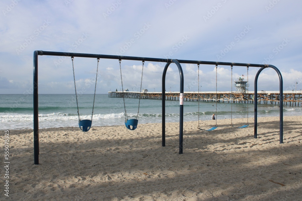 Swing set on beach near pier
