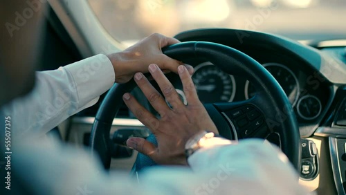 close up male hand honking the car horn during driving a car at day. man in white shirt drives the car and honking the car horn. photo