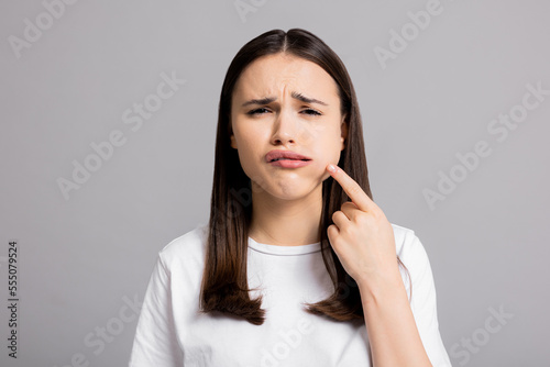 Fotografía Crying tired sad woman suffers from painful toothache dental illness pointing on teeth standing on grey background in studio isolated wearing basic white t-shirt