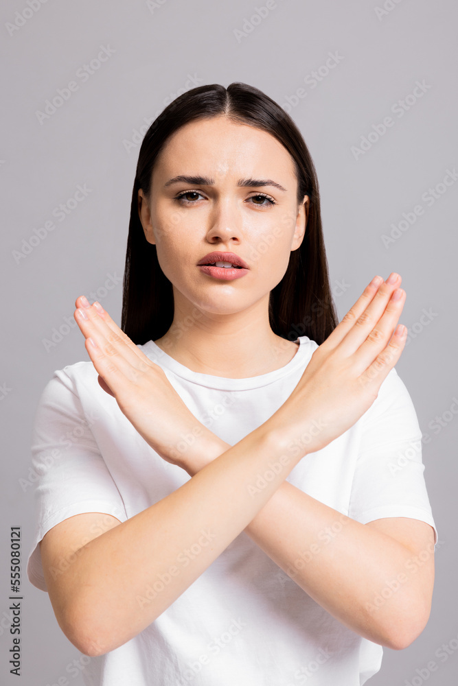 Portrait of young serious young woman shows stop gesture. making cross with arms and looking displeased at camera, prohibiting forbides something, standing over grey background. Portrait of young serious young woman shows stop gesture. making cross with arms and looking displeased at camera, prohibiting forbides something, standing over grey background.