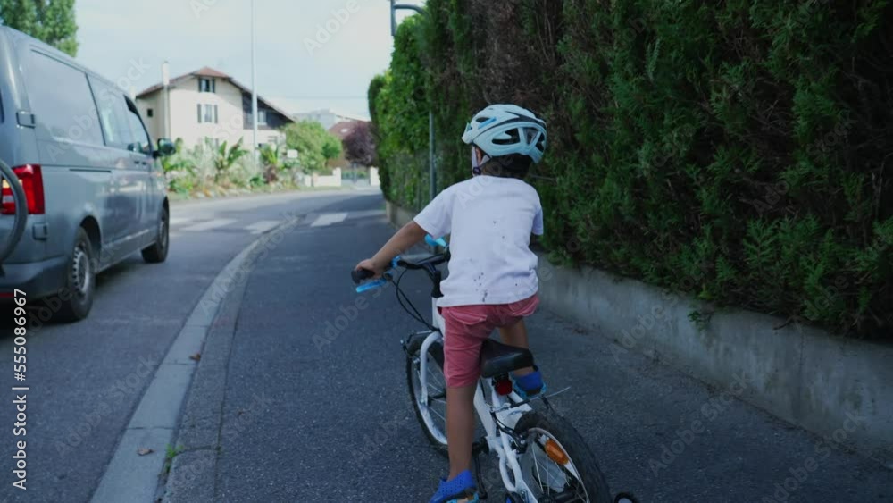 Little boy riding bike in city street. Child cyclist rides bicycle at sidewalk wearing helmet Little boy riding bike in city street. Child cyclist rides bicycle at sidewalk wearing helmet