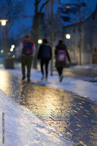 Slippery and icy (Blitzeis, Glatteis) path in the city. 3 boys on the dangerous way to school. In the early winter morning. Germany, Nurtingen.