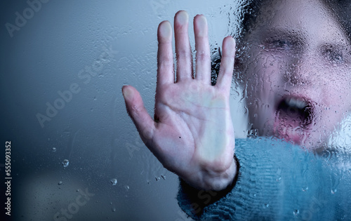 Conceptual image  Protect children and young underage people from violence  exploitation  abuse  and neglect. Young girl showing stop gesture from behind wet glass. Copy space.