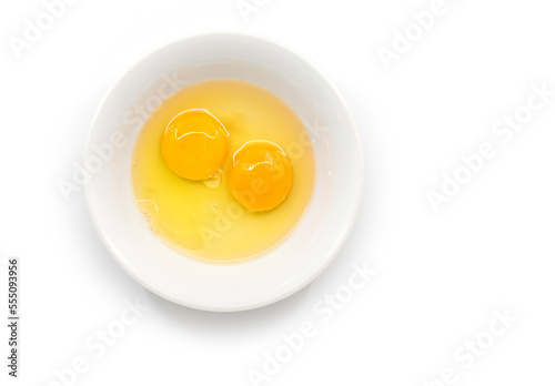 Isolated raw chicken eggs, top view of two raw egg yolk in white bowl on white background.