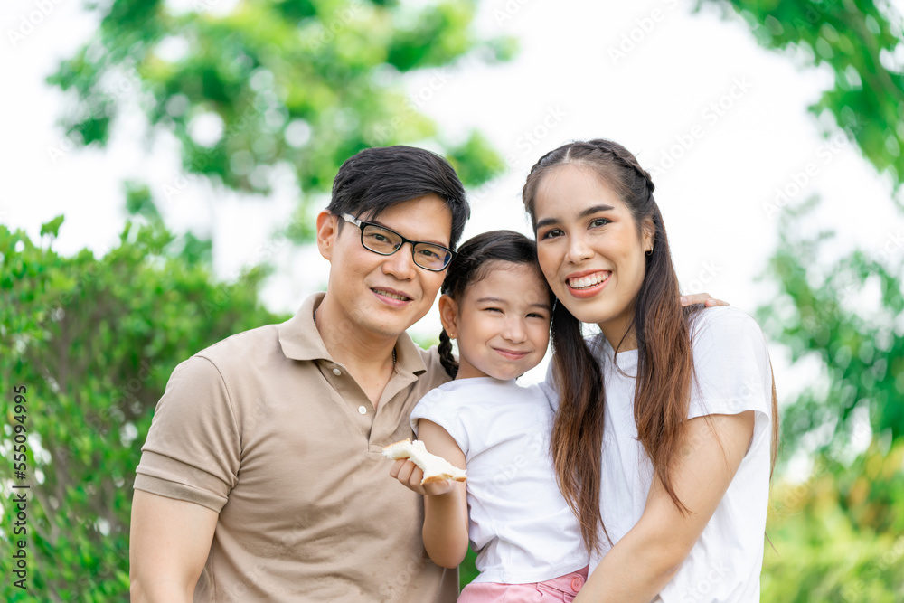 Young Asian parents doing activities eating and playing with their daughter in the front yard during the holidays happily. Young Asian parents doing activities eating and playing with their daughter in the front yard during the holidays happily.