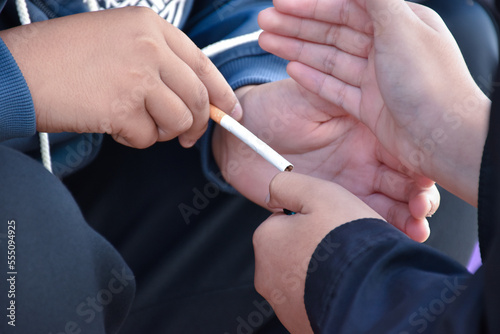 Boys learning to smoke with the same age friends in the area behind the school fence which teachers cannot see, bad influence of secondary school or junior high school life, addiction.