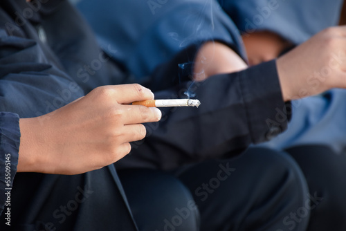 Boys learning to smoke with the same age friends in the area behind the school fence which teachers cannot see, bad influence of secondary school or junior high school life, addiction.
