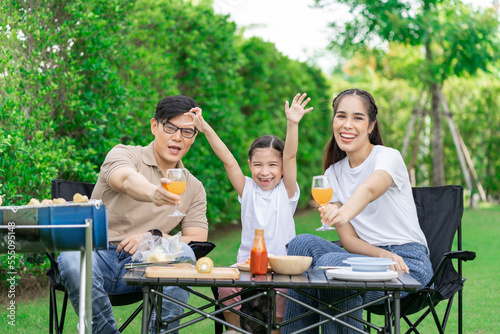 Young Asian parents doing activities eating and playing with their daughter in the front yard during the holidays happily.