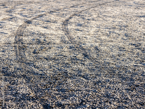 Car track trace on f frozen surface of a car park. Winter season. Cold time.