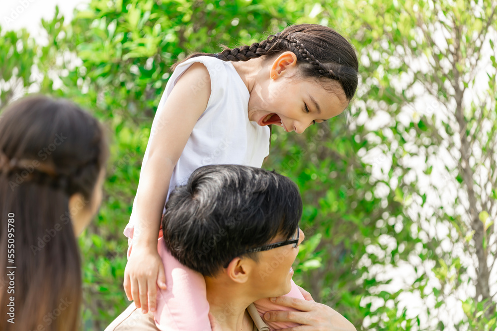 Young Asian parents doing activities eating and playing with their daughter in the front yard during the holidays happily. Young Asian parents doing activities eating and playing with their daughter in the front yard during the holidays happily.