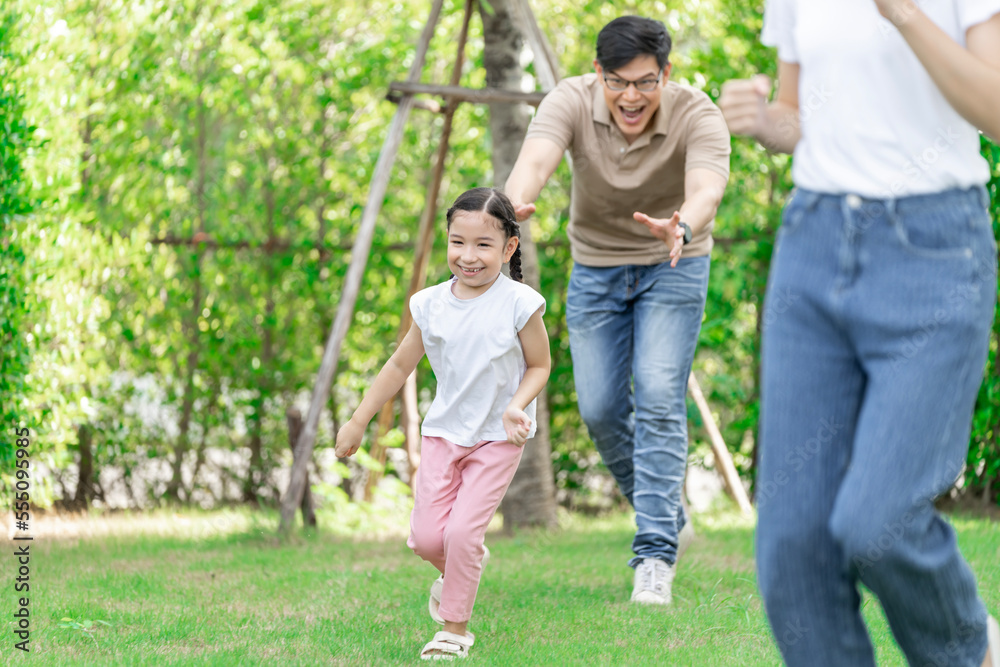 Young Asian parents doing activities eating and playing with their daughter in the front yard during the holidays happily.