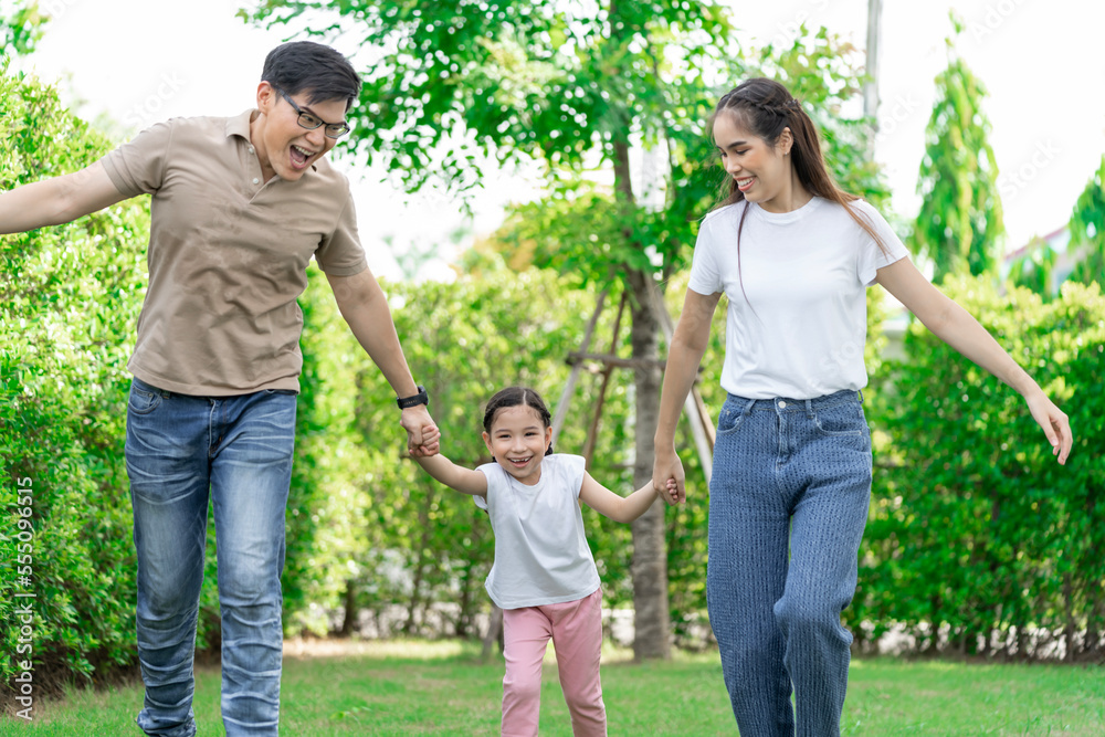 Young Asian parents doing activities eating and playing with their daughter in the front yard during the holidays happily.