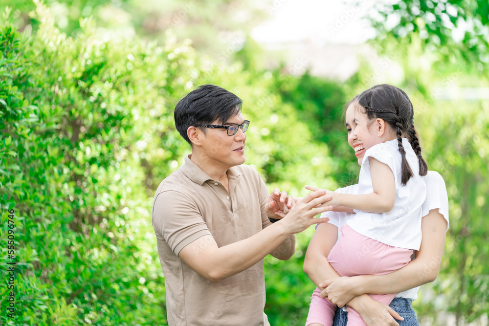 Young Asian parents doing activities eating and playing with their daughter in the front yard during the holidays happily. Young Asian parents doing activities eating and playing with their daughter in the front yard during the holidays happily.