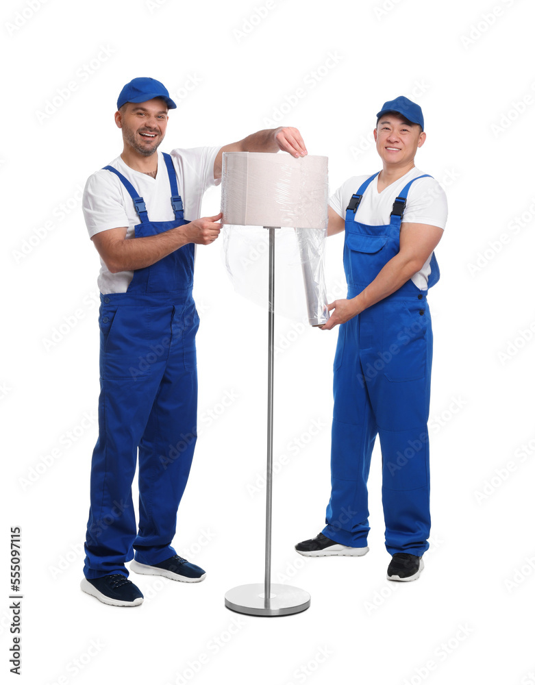 Workers wrapping lamp in stretch film on white background Workers wrapping lamp in stretch film on white background