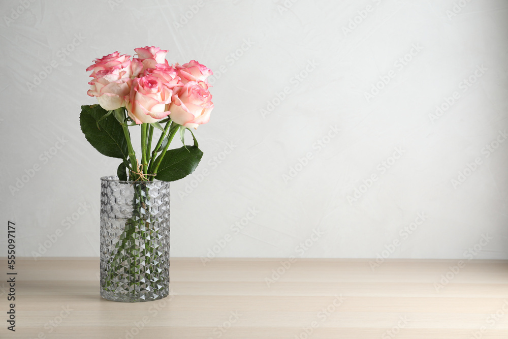 Vase with beautiful pink roses on wooden table. Space for text Vase with beautiful pink roses on wooden table. Space for text