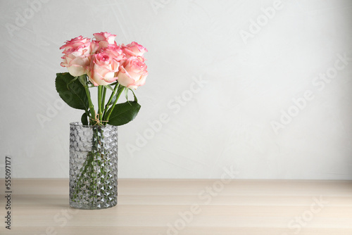Vase with beautiful pink roses on wooden table. Space for text © New Africa