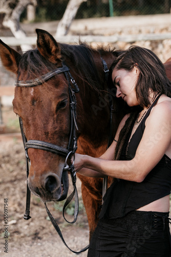 Amazon girl holding the horse's reins and looking at camera.