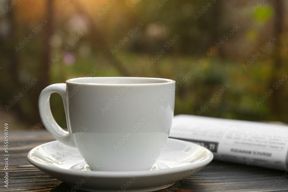 White cup with coffee and newspaper on wooden table, closeup. Morning ritual White cup with coffee and newspaper on wooden table, closeup. Morning ritual
