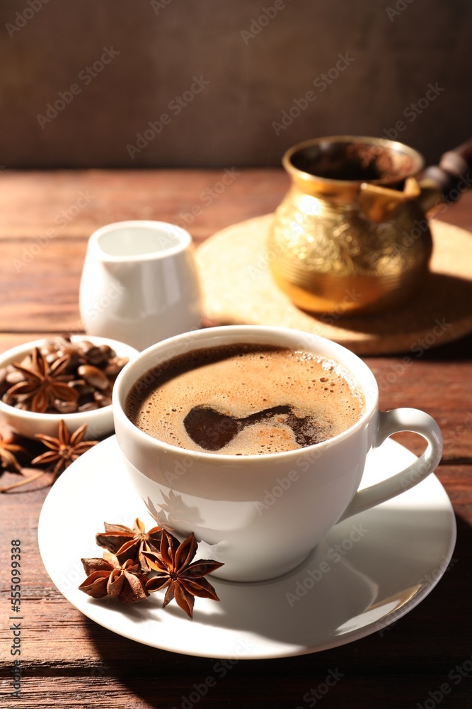 Cup of aromatic hot coffee with anise stars on wooden table Cup of aromatic hot coffee with anise stars on wooden table