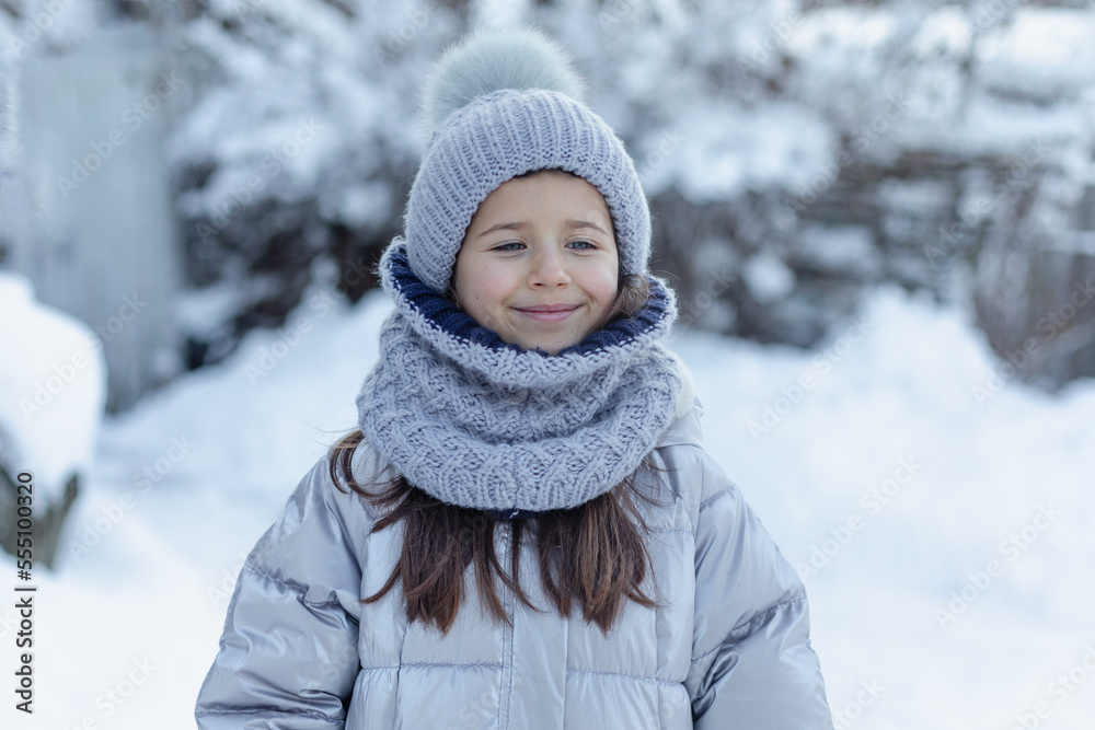 little girl in a gray knitted hat and scarf in winter outdoors, outside, winter season