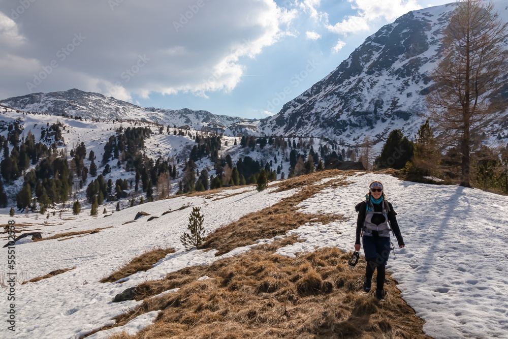Woman walking on idyllic snow covered hiking trail to the snowcapped mountain peak of Zirbitzkogel, Seetal Alps, Styria (Steiermark), Austria, Europe. Landscape of hills, forest, pastures and ridges