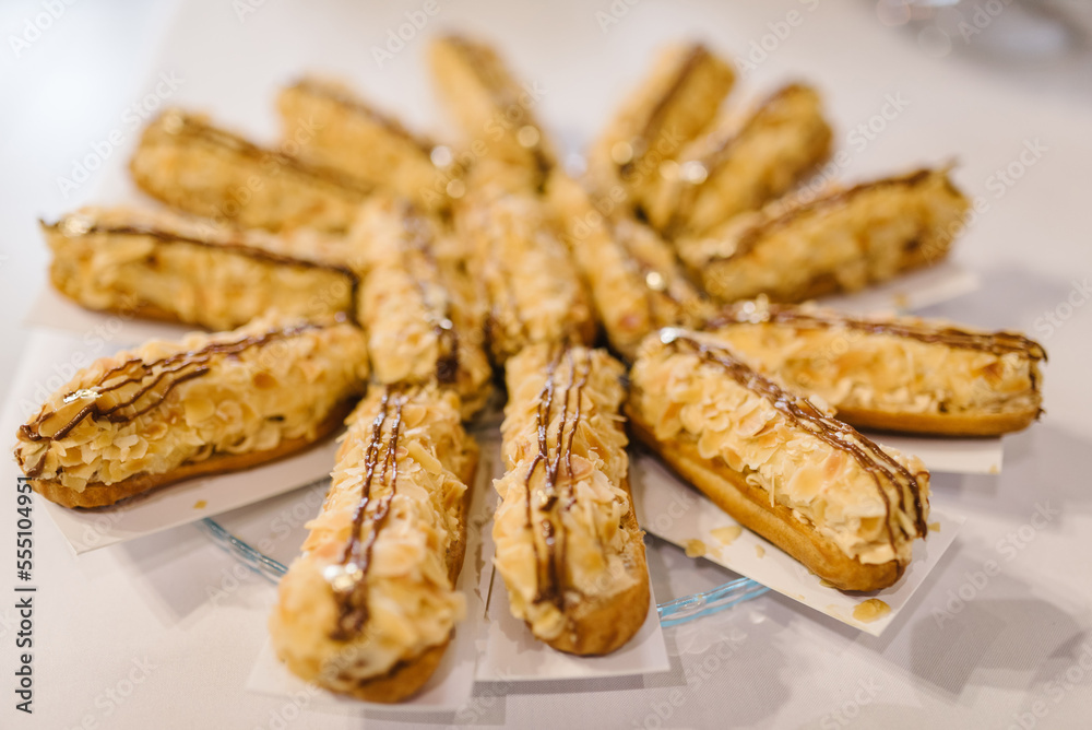 Eclairs sprinkled with almond flakes. Eclairs with cream. Close up. Candy bar. Eclairs sprinkled with almond flakes. Eclairs with cream. Close up. Candy bar.