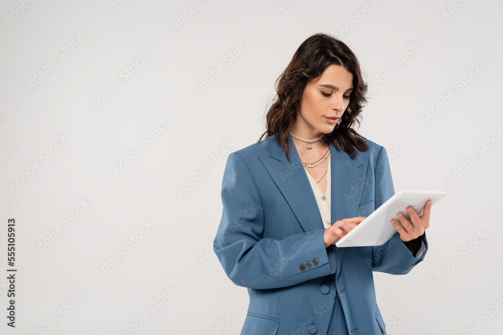 young woman in blue fashionable jacket using digital tablet isolated on grey young woman in blue fashionable jacket using digital tablet isolated on grey