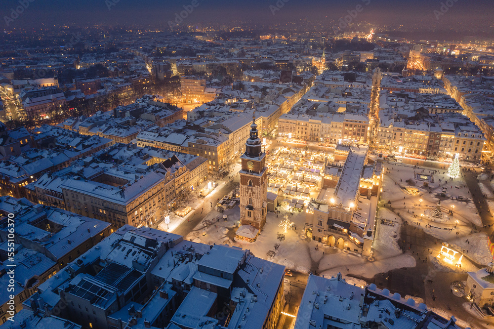 Snow covered old town in Krakow with a view of the Christmas Market photographed in the blue hour.