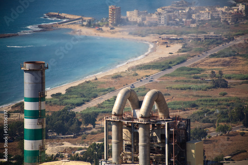 The smoke stack of a cement factory with the Chekka coast inthe background.