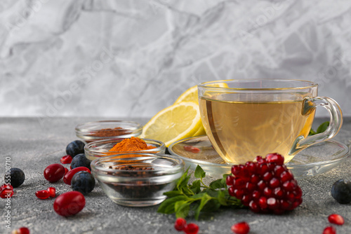 Cup with delicious immunity boosting tea and ingredients on grey table