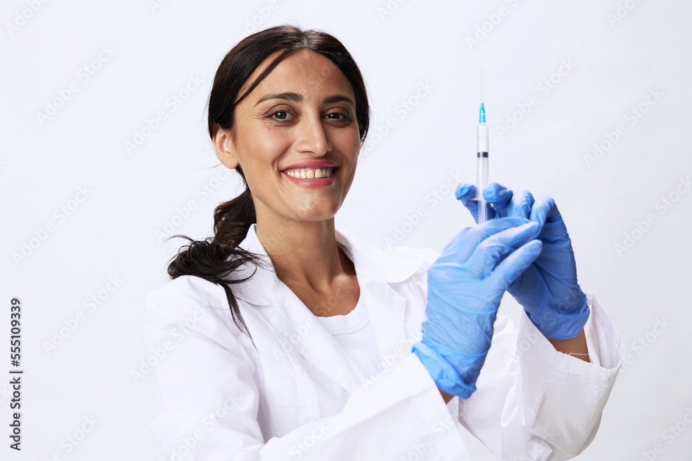 Woman doctor with syringe in hand in medical gown on white background nurse in blue gloves, covid-19 vaccine, shot for pain, concept of health and science Woman doctor with syringe in hand in medical gown on white background nurse in blue gloves, covid-19 vaccine, shot for pain, concept of health and science