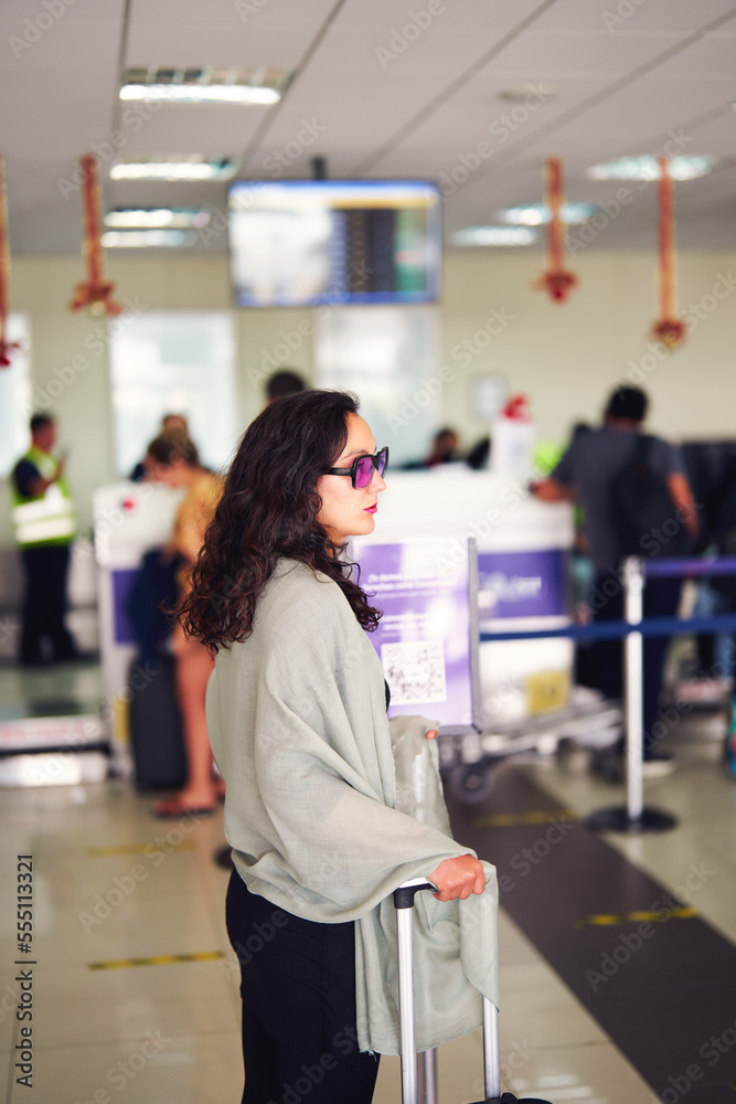 profile portrait of latin woman in airport with suitcase pensive looking while checking in profile portrait of latin woman in airport with suitcase pensive looking while checking in