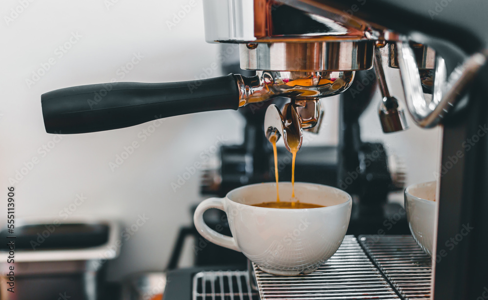 Coffee extraction from the coffee machine with a portafilter pouring coffee into a cup,Espresso poruing from coffee machine at coffee shop Coffee extraction from the coffee machine with a portafilter pouring coffee into a cup,Espresso poruing from coffee machine at coffee shop