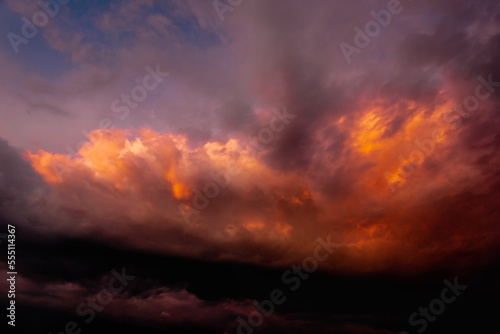 colorful dramatic sky with clouds, smoking cumulonimbus clouds reflect the golden light of the dawn sun. 