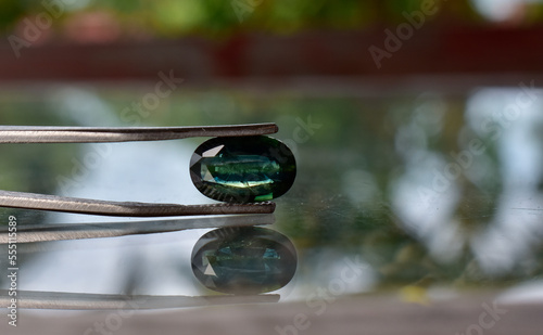 A beautiful shiny green gem. in the gem clamp